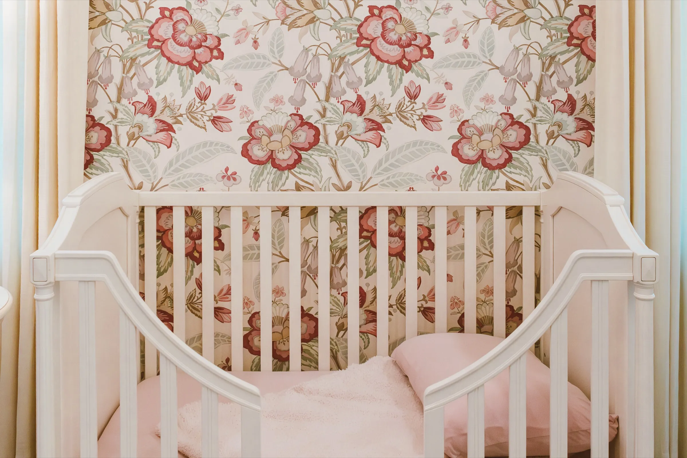 Nursery with floral wallpaper and a white crib