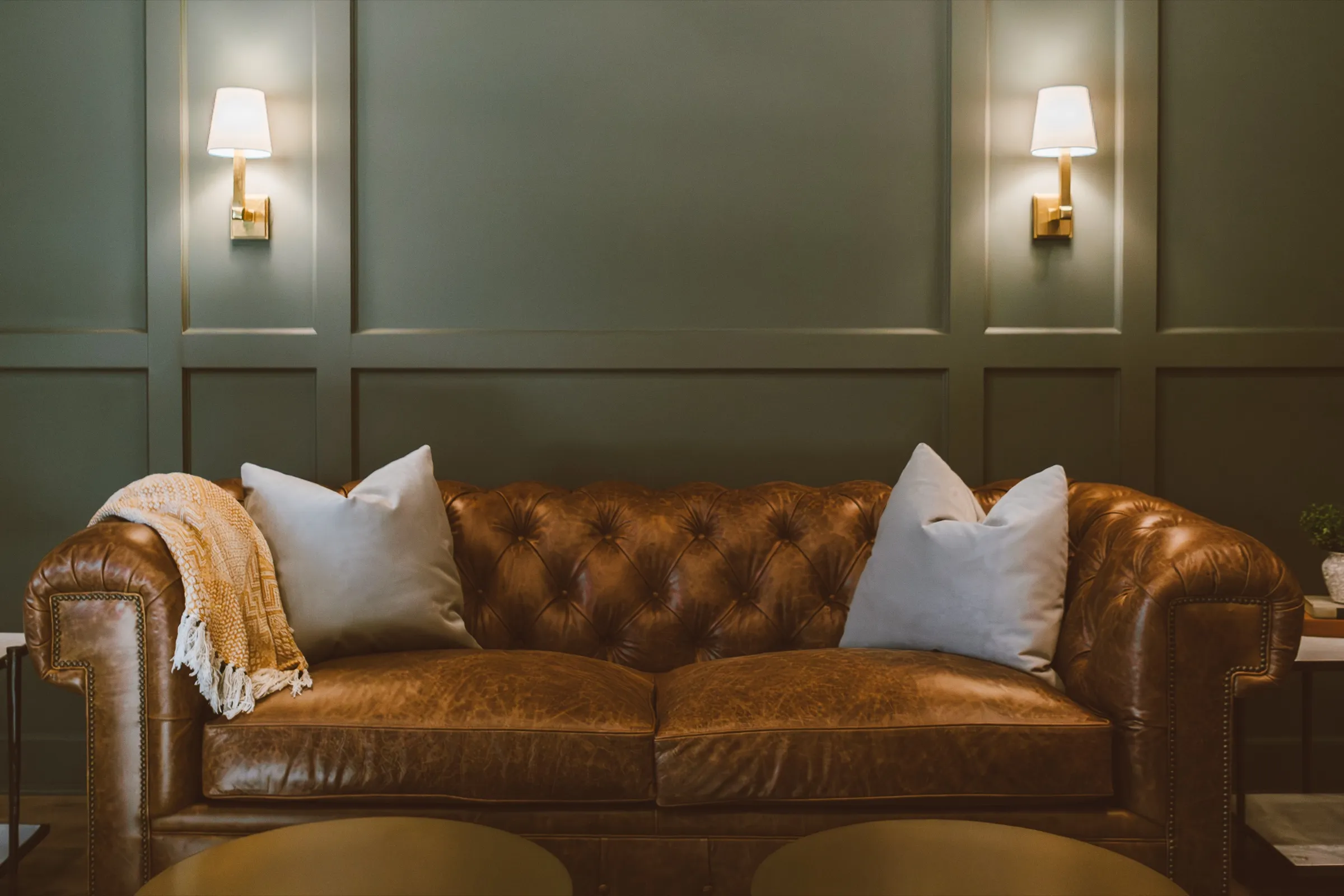 Green paneled den with a tufted leather sofa