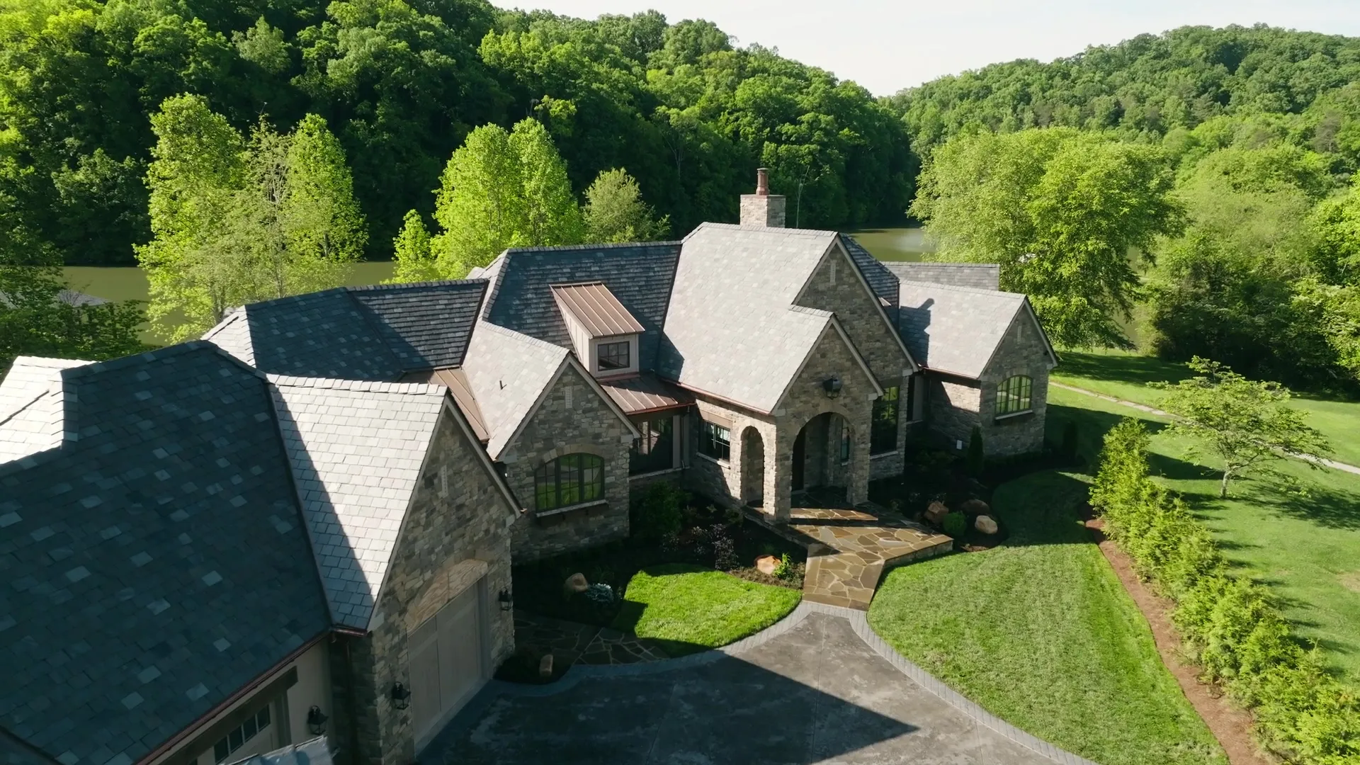 Aerial view of a stone custom home above the lake