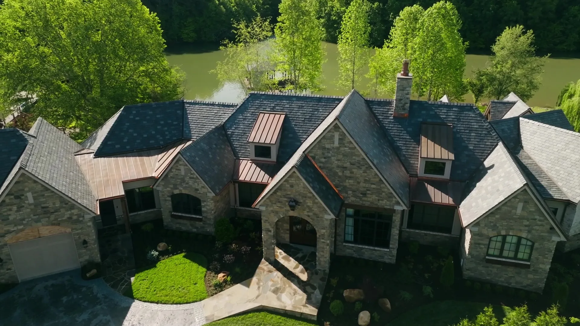 Aerial view of a stone Biles custom home and its grounds