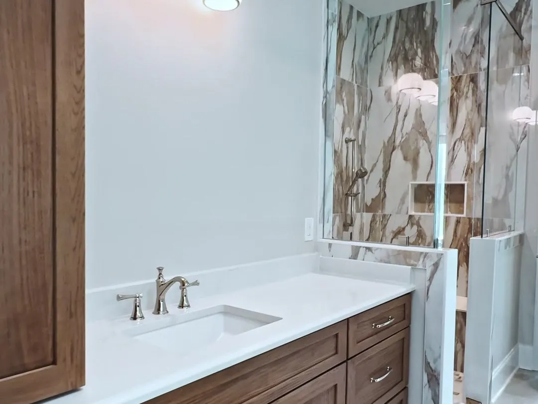 Bathroom vanity with marble tile and warm wood cabinetry