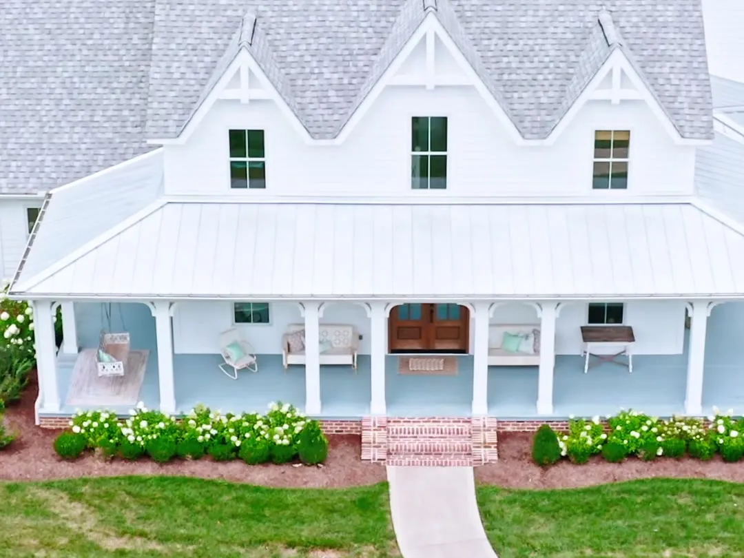 The Countryside Residence, a white farmhouse with a wrap-around porch on open land